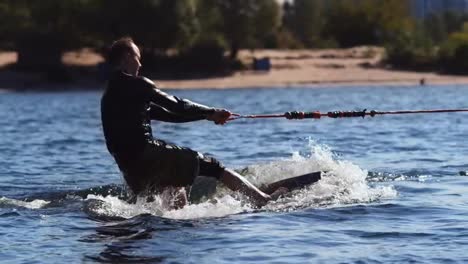 Wakesurfer-riding-board-on-waves-in-sunny-day.-Extreme-water-sport