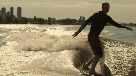 Surfer-riding-wave-on-wakeboard-in-slow-motion.-Man-surfing-at-sunset
