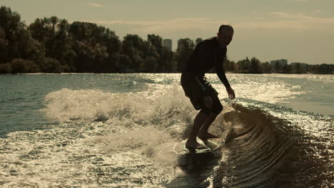 Sportsman-riding-on-wake-surf-at-sunset.-Sportive-man-training-on-surf-board