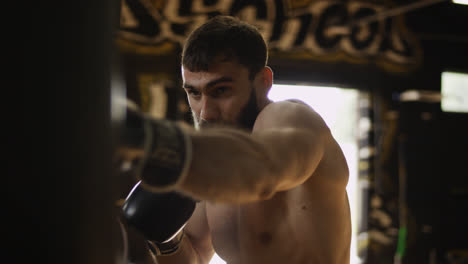 Boxer-hitting-punching-bag-in-gym-in-boxing-gloves.-Athlete-working-hard