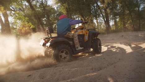 Man-riding-atv-on-sand-picking-up-pillar-of-dust.-Modern-guy-driving-quadbike