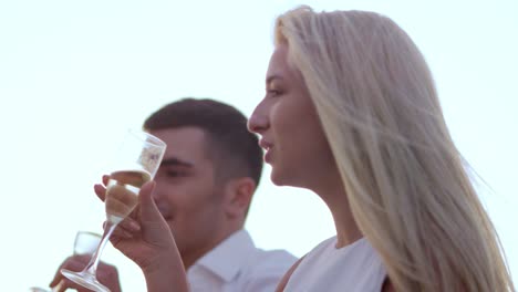 Fashionable-young-couple-drinking-champagne-at-sunset.-Happy-people-celebrating