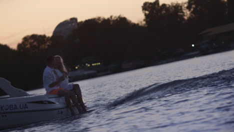 Young-people-sitting-on-floating-motor-boat-at-sunset.-Love-couple-at-yacht