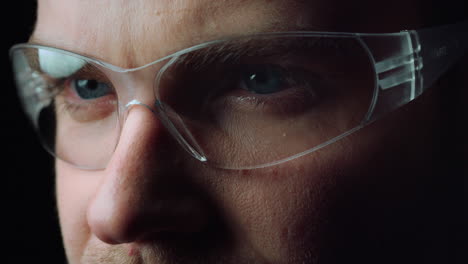 Close-up-of-face-of-focused-man-opening-beautiful-blue-eyes-with-glasses.