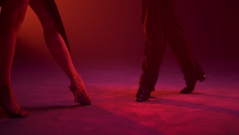 Dance-couple-feet-moving-on-stage.-Latin-dancers-legs-practicing-indoors.