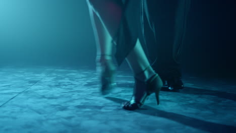 Couple-legs-dancing-tango-on-stage.-Dancers-feet-performing-latin-dance-in-dark.