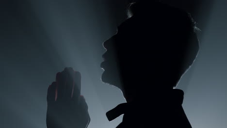 Silhouette-man-praying-in-darkness.-Male-person-whispering-prayer-indoors.