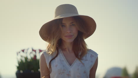 Sensual-blonde-woman-in-sunhat-looking-at-camera-in-bright-summer-day-outside.