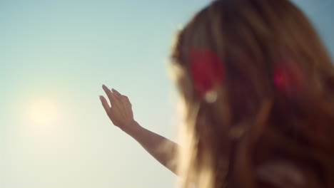 Close-up-sunbeam-throught-woman-fingers.-Woman-back-with-hand-touching-sunshine.