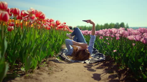 Blossomed-tulip-filed-in-spring-girl-looking-at-mobile-phone-screen-in-sunny-day
