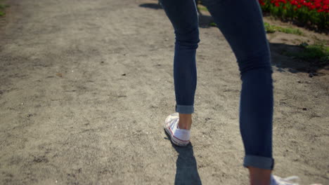 Closeup-woman-legs-walking-in-sport-shoes.-Unknown-girl-going-in-white-sneakers.