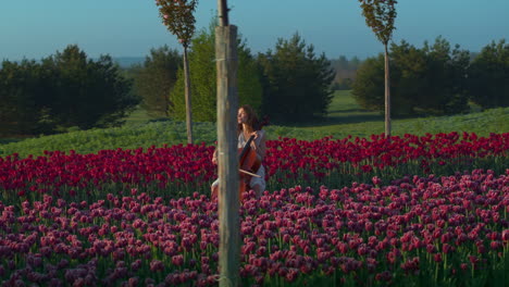 Unrecognizable-young-woman-playing-violoncello-in-blooming-field-in-springtime.