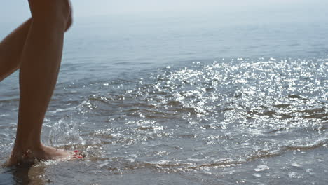 Young-girl-feet-jumping-on-sea-waves-close-up.-Slim-woman-splashing-ocean-water.