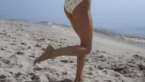Bare-woman-legs-stepping-on-sand-beach-close-up.-Carefree-girl-walking-to-waves.