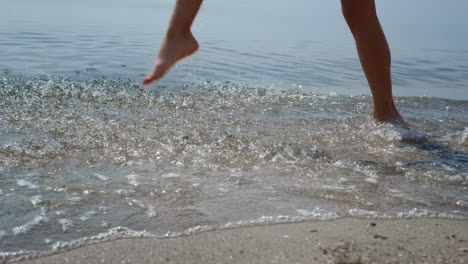 Barfüßiges-Mädchen,-Das-Wasser-Spritzt-Und-Meereswellen-Aus-Nächster-Nähe-Tritt.-Beine-Gehen-Sand.