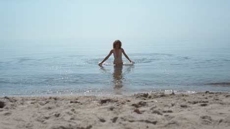 Happy-woman-coming-out-ocean-splashing-water.-Girl-running-to-sand-seashore.
