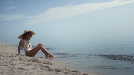 Entspannte-Frau-Sitzt-Am-Strandsand-Und-Wäscht-Ihre-Beine-In-Den-Wellen-Des-Ozeans.-Mädchen-Beim-Sonnenbaden.
