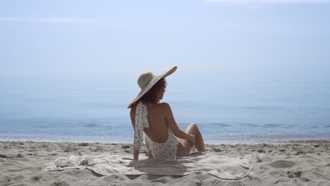 Tempting-woman-sitting-beach-wearing-swimsuit-in-front-beautiful-ocean-waves.