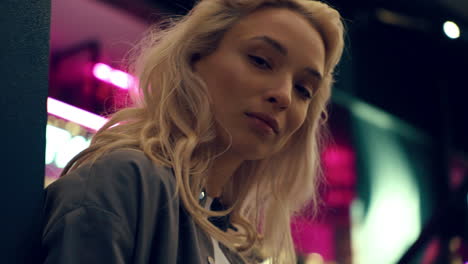 Blonde-model-face-looking-camera-in-neon-lights-in-night-city.