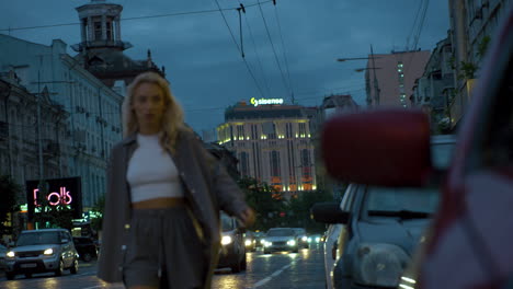 Female-model-walking-towards-camera-at-evening-city-traffic-lights.