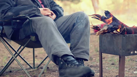 Tourist-sitting-on-camp-chair-near-campfire.-Outdoor-recreation
