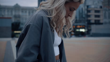 Blonde-woman-looking-down-in-evening-city-urban-background.
