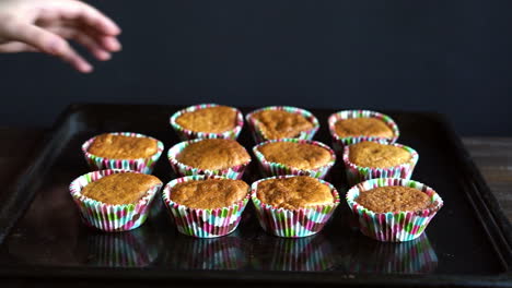 Chef-take-away-cupcake-from-baking-tray.-Cooked-cupcakes-on-baking-pan