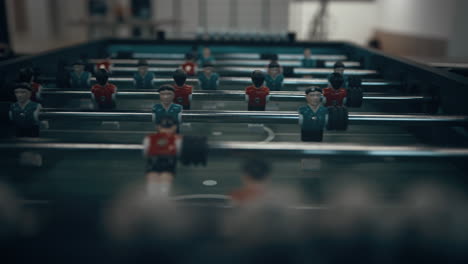 Closeup-miniature-plastic-figures-on-football-table.-Children-hands-revolve-rods