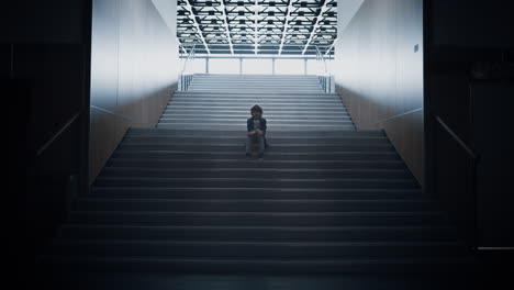 Lonely-schoolchild-sitting-alone-on-school-staircase-closeup.-Boy-hide-in-hall.